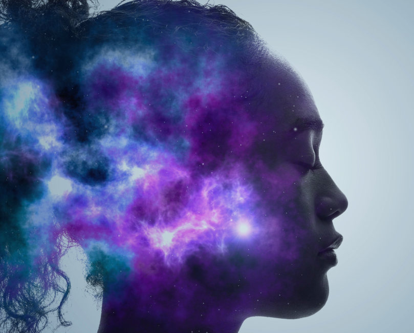 A graphic of a woman looking serene with her eyes closed. Overlaid on her face is art of the universe.