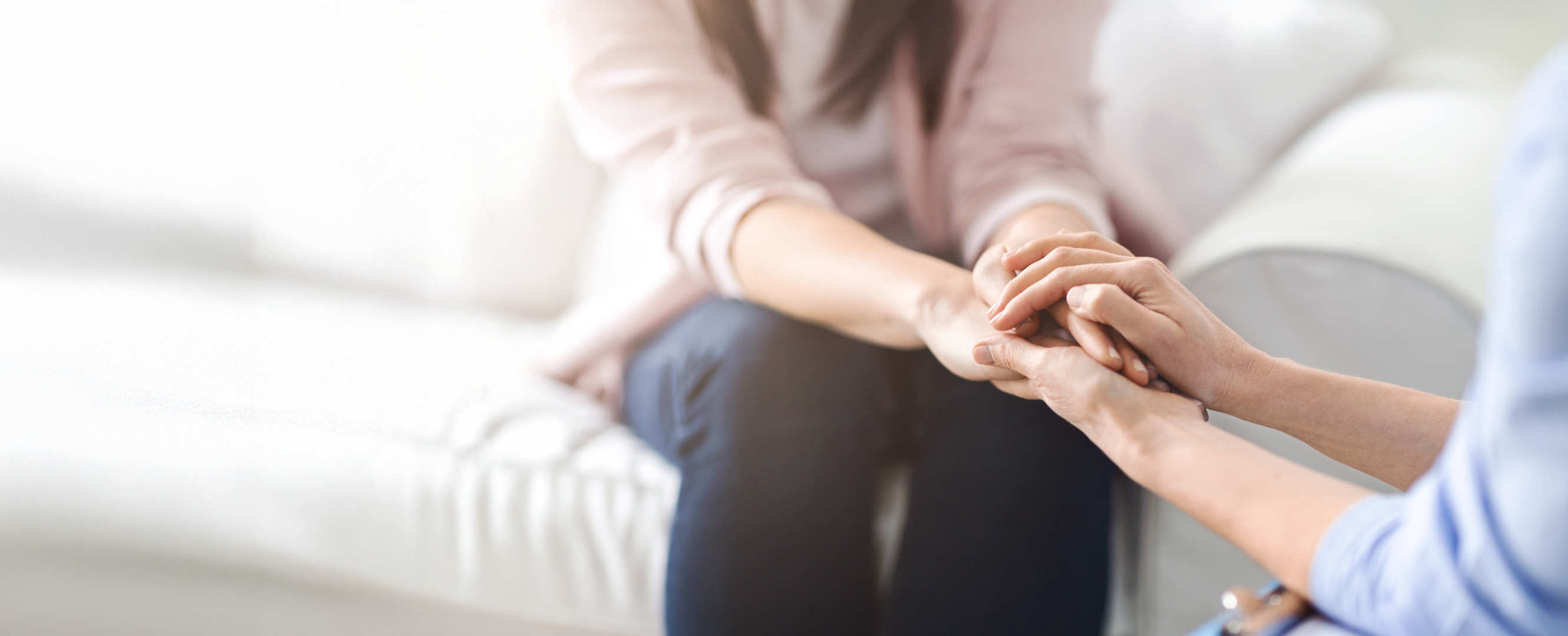 A blurred image of two people holding hands and sitting accross from each other.