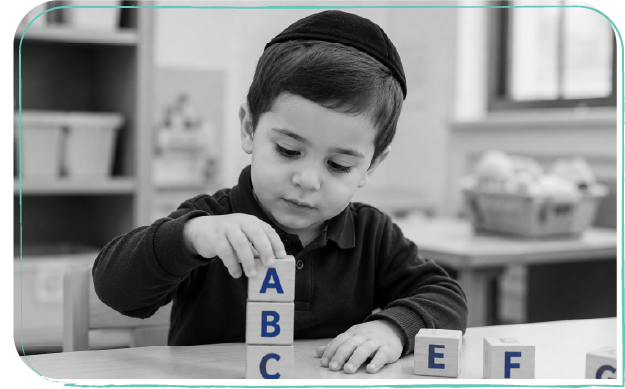 A student stacking alphabet blocks in the classroom
